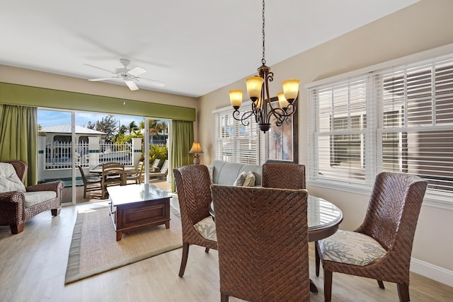 dining area with light wood-style flooring, baseboards, and ceiling fan with notable chandelier