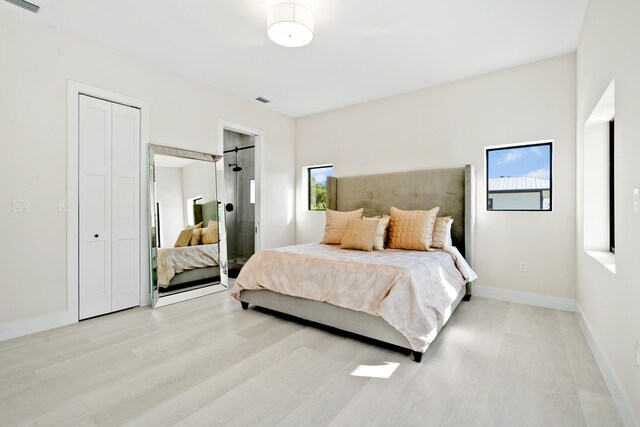 bedroom with multiple windows, connected bathroom, and light hardwood / wood-style floors