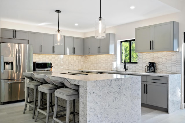 kitchen with tasteful backsplash, sink, light stone countertops, and appliances with stainless steel finishes