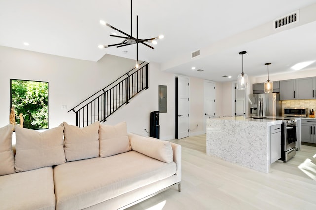 living room featuring an inviting chandelier, electric panel, and light hardwood / wood-style flooring