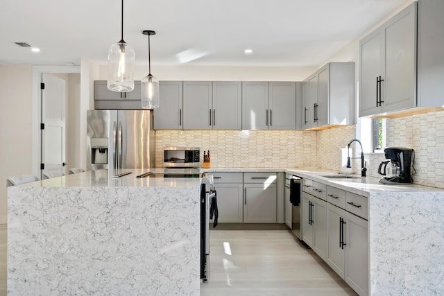 kitchen featuring pendant lighting, appliances with stainless steel finishes, sink, and decorative backsplash