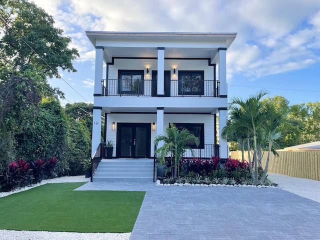 modern home with french doors, a balcony, covered porch, and a front lawn