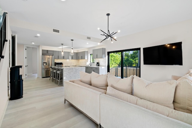 living room featuring an inviting chandelier, sink, and light wood-type flooring