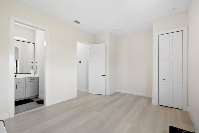 unfurnished bedroom with connected bathroom, light hardwood / wood-style floors, and a closet