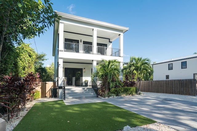 back of property featuring a yard, a balcony, and a porch