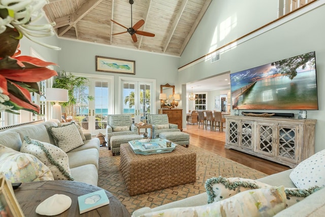 living room featuring wood ceiling, hardwood / wood-style flooring, ceiling fan, beam ceiling, and french doors