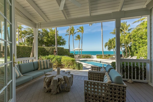 sunroom / solarium featuring lofted ceiling with beams and a water view