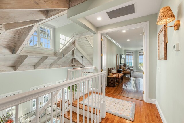 hall with beam ceiling, ornamental molding, and light wood-type flooring