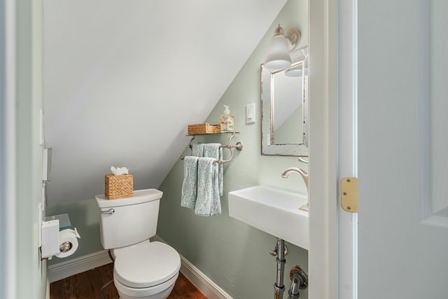 bathroom with hardwood / wood-style flooring, sink, toilet, and vaulted ceiling