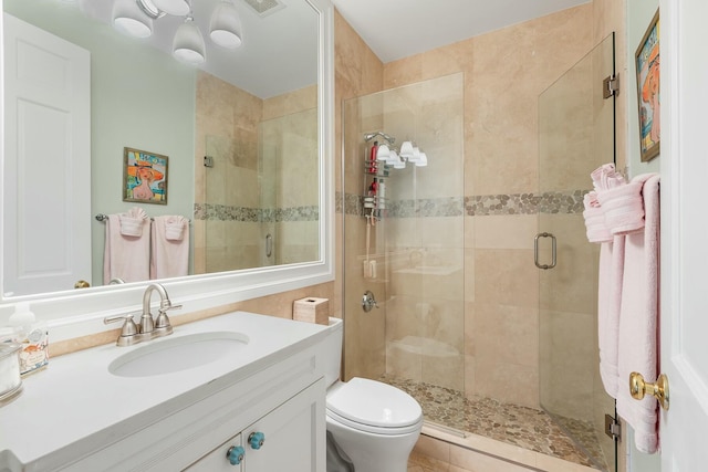 bathroom with a shower with door, vanity, and toilet