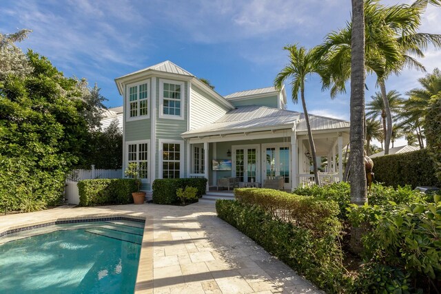 rear view of house with a patio, a fenced in pool, and french doors