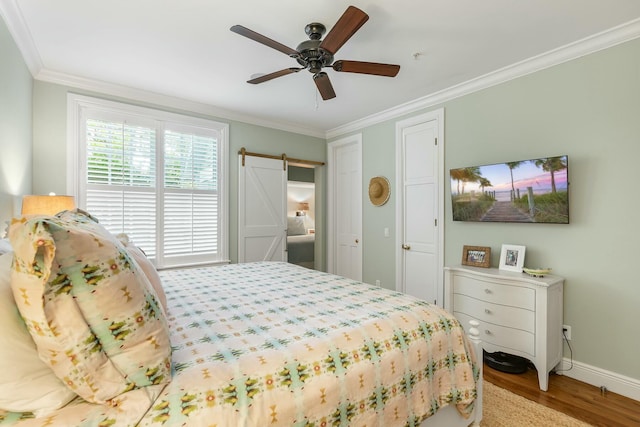 bedroom featuring crown molding, a barn door, ceiling fan, and light wood-type flooring