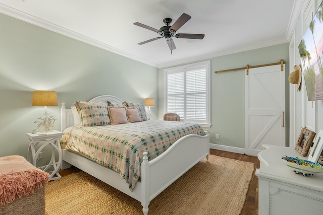 bedroom with crown molding, a barn door, ceiling fan, and hardwood / wood-style flooring