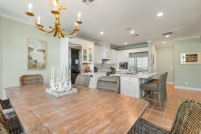 dining space featuring crown molding, a chandelier, sink, and light tile patterned floors