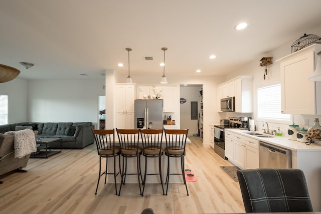 kitchen with appliances with stainless steel finishes, pendant lighting, sink, white cabinets, and a center island