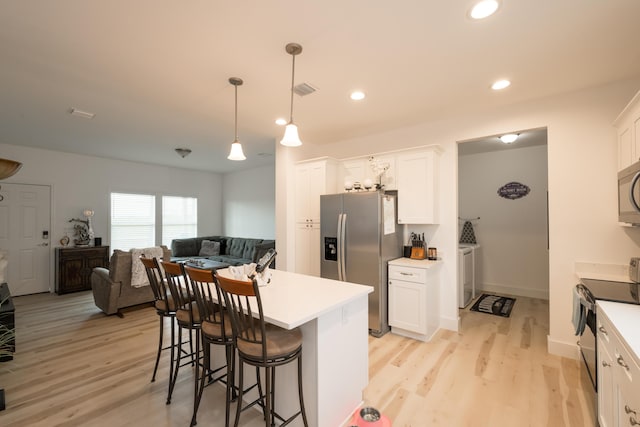 kitchen with appliances with stainless steel finishes, white cabinets, independent washer and dryer, and decorative light fixtures