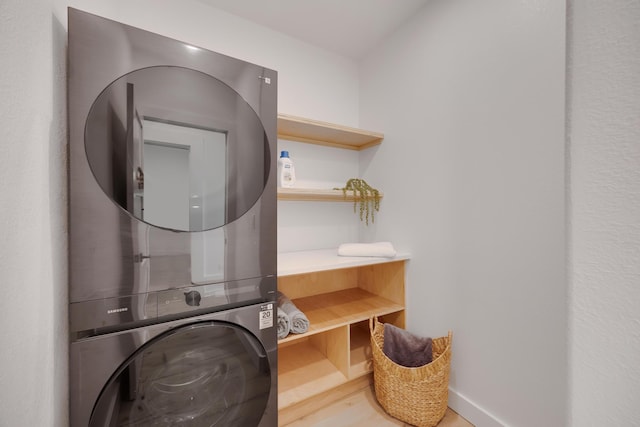 washroom with wood-type flooring and stacked washer / dryer