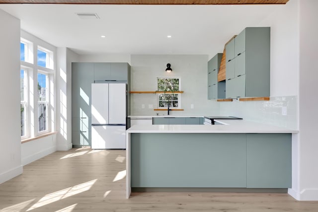 kitchen with tasteful backsplash, kitchen peninsula, a healthy amount of sunlight, and white refrigerator