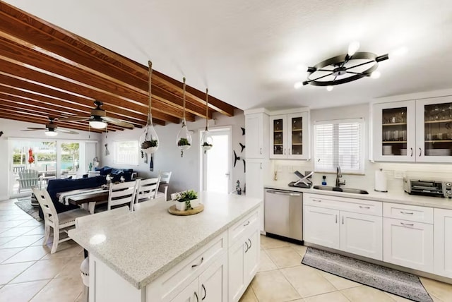 kitchen with white cabinetry, stainless steel dishwasher, beam ceiling, and sink