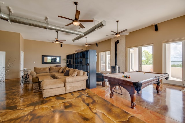 playroom featuring ceiling fan, billiards, concrete floors, and a wood stove