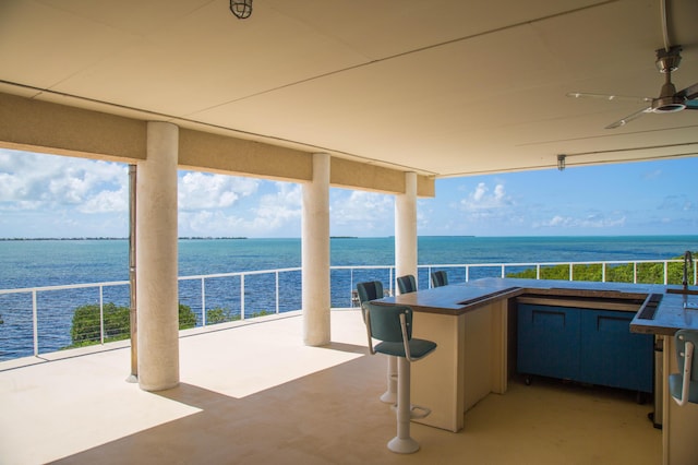 view of patio / terrace with a water view, ceiling fan, and exterior bar