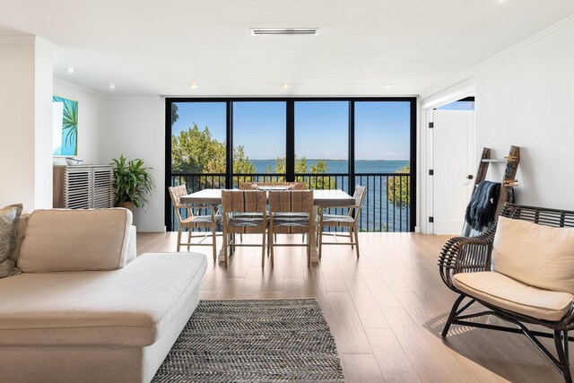 living room featuring crown molding, hardwood / wood-style flooring, floor to ceiling windows, and a water view