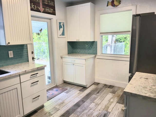 kitchen featuring plenty of natural light, light hardwood / wood-style floors, light stone countertops, and white cabinets