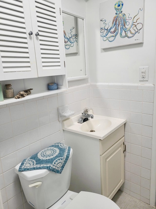 bathroom with vanity, toilet, and tile walls