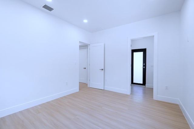 empty room with light wood-style floors, recessed lighting, baseboards, and visible vents