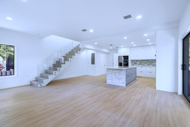 kitchen featuring electric panel, decorative backsplash, stainless steel fridge, white cabinetry, and modern cabinets