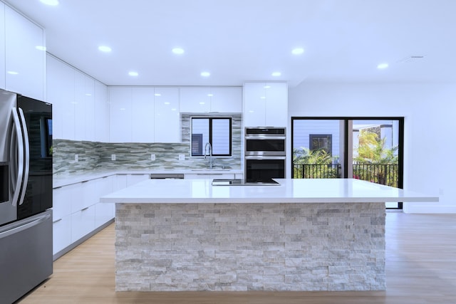 kitchen featuring a center island, stainless steel appliances, white cabinets, modern cabinets, and a sink