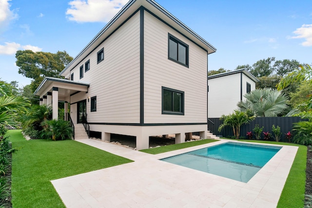 back of house with a patio, a fenced in pool, fence, and a lawn