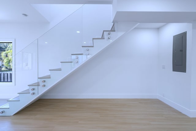 stairway with electric panel, baseboards, and wood finished floors