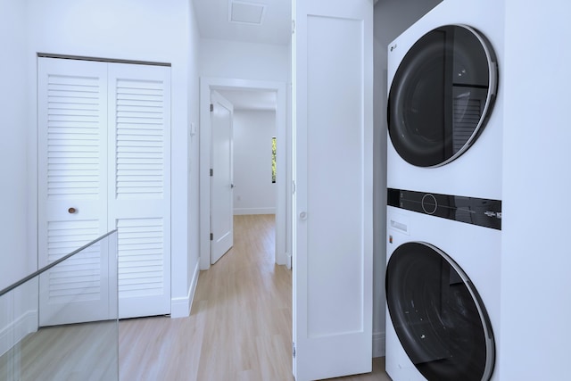 laundry room with visible vents, baseboards, stacked washer and dryer, laundry area, and light wood-style floors