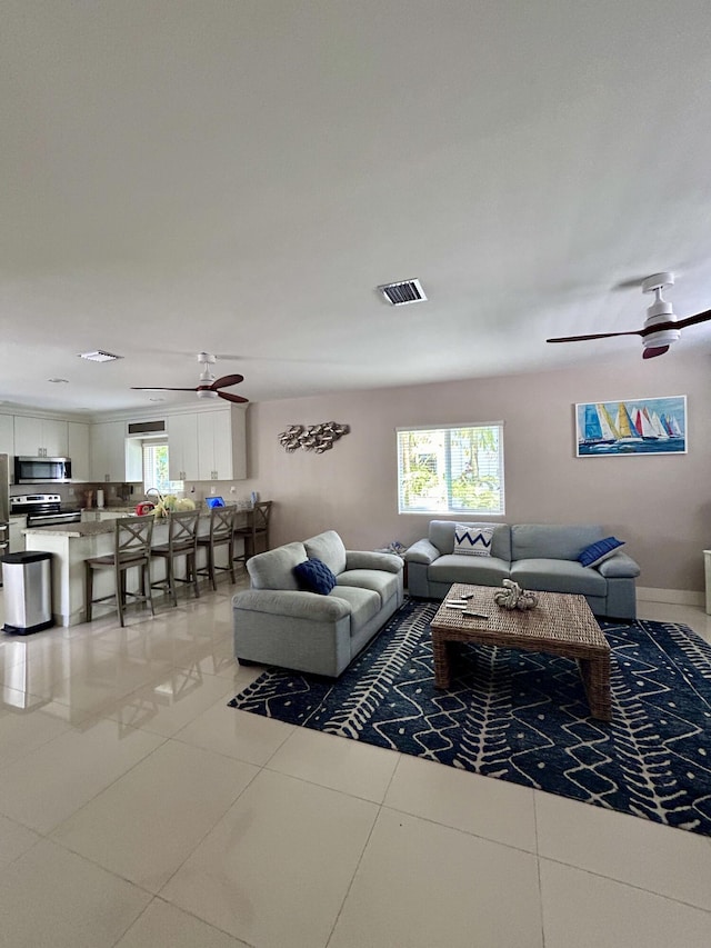 living room featuring ceiling fan, plenty of natural light, and tile patterned flooring