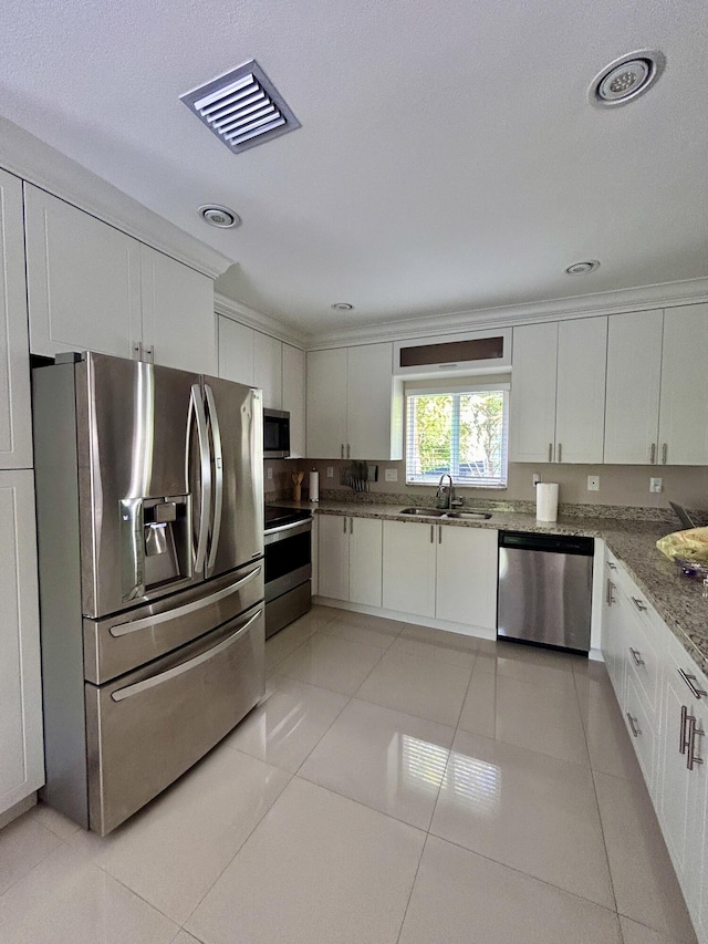 kitchen featuring stainless steel appliances, sink, light tile patterned floors, and white cabinets