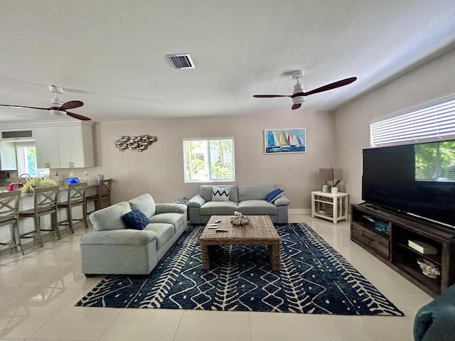 tiled living room with a wealth of natural light and ceiling fan