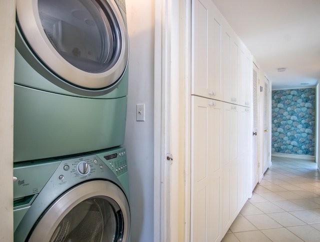 laundry area featuring laundry area, stacked washer and dryer, light tile patterned flooring, and wallpapered walls