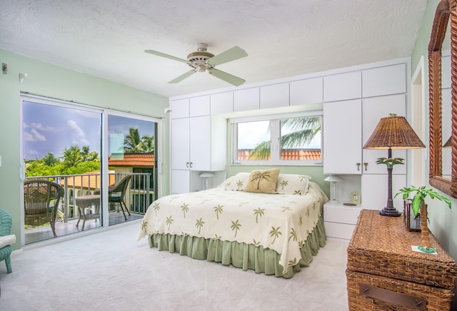 carpeted bedroom featuring access to outside, a ceiling fan, and a textured ceiling