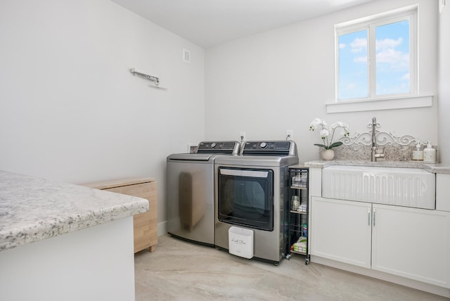 washroom with cabinets, independent washer and dryer, and sink