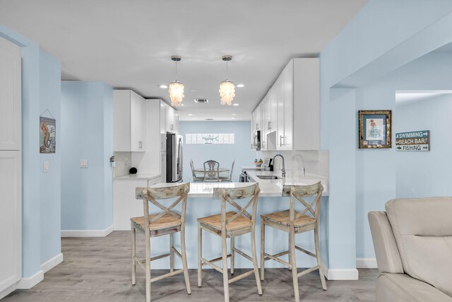 kitchen featuring stainless steel fridge, light hardwood / wood-style flooring, white cabinets, and kitchen peninsula