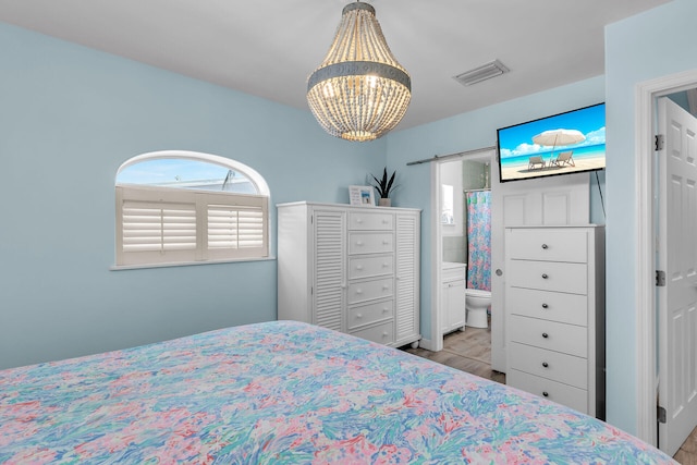 bedroom with an inviting chandelier, connected bathroom, and a barn door