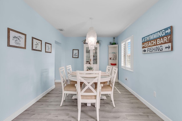 dining room with light hardwood / wood-style floors and a chandelier