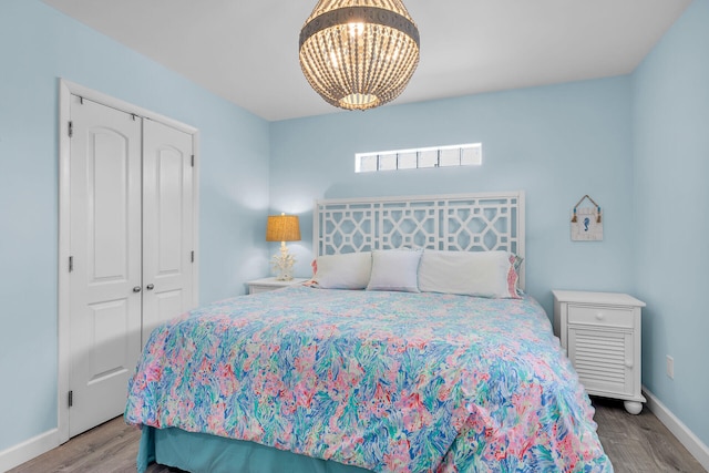 bedroom featuring a notable chandelier, hardwood / wood-style flooring, and a closet