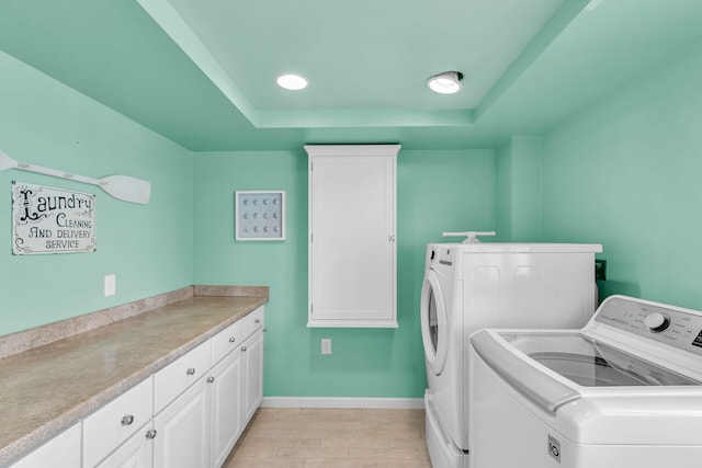 washroom featuring cabinets, independent washer and dryer, and light hardwood / wood-style floors