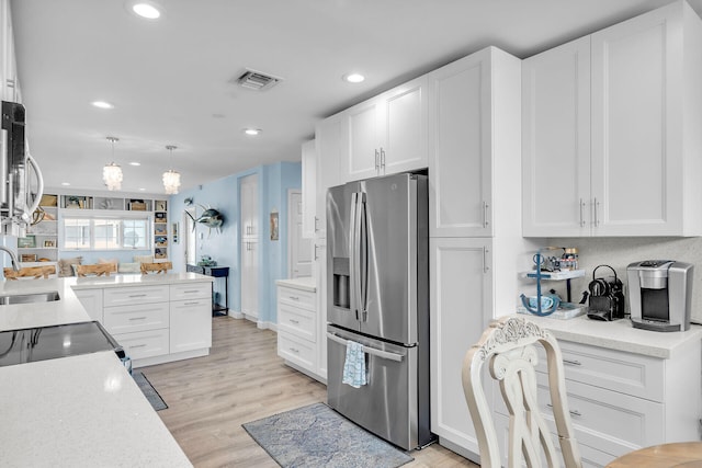 kitchen featuring stainless steel refrigerator with ice dispenser, decorative light fixtures, sink, and white cabinets