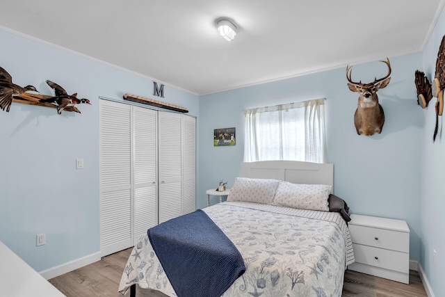 bedroom with ornamental molding, light hardwood / wood-style floors, and a closet