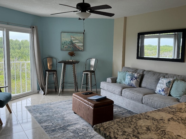 tiled living room with a ceiling fan, a wealth of natural light, and a textured ceiling