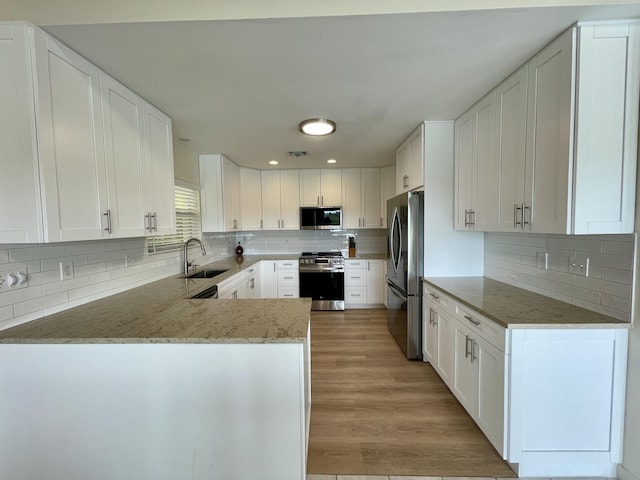 1165 Lagoon Dr, Summerland, FL 33042 - kitchen featuring appliances with stainless steel finishes, a sink, backsplash, light stone countertops, and white cabinetry