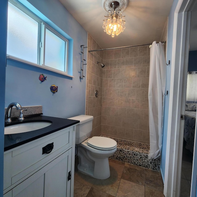 bathroom with toilet, vanity, stone finish flooring, and a tile shower